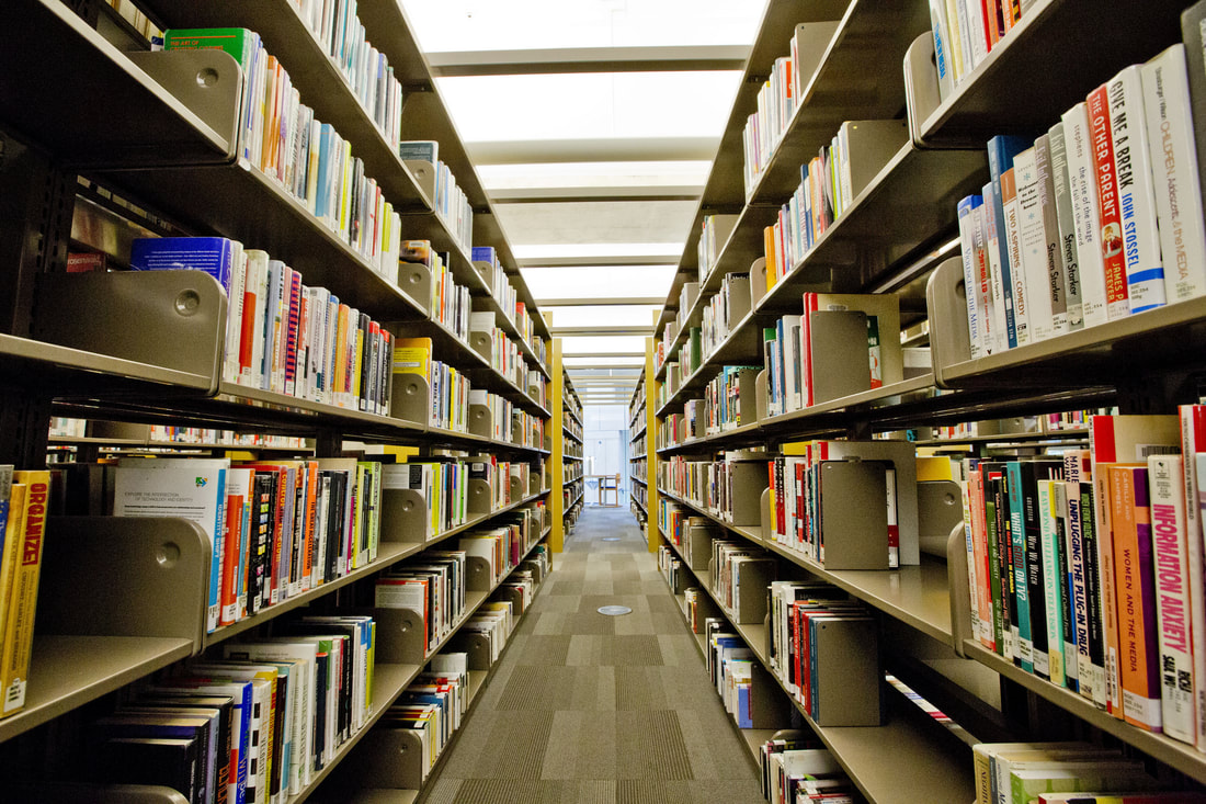 Library shelves leading to bright room