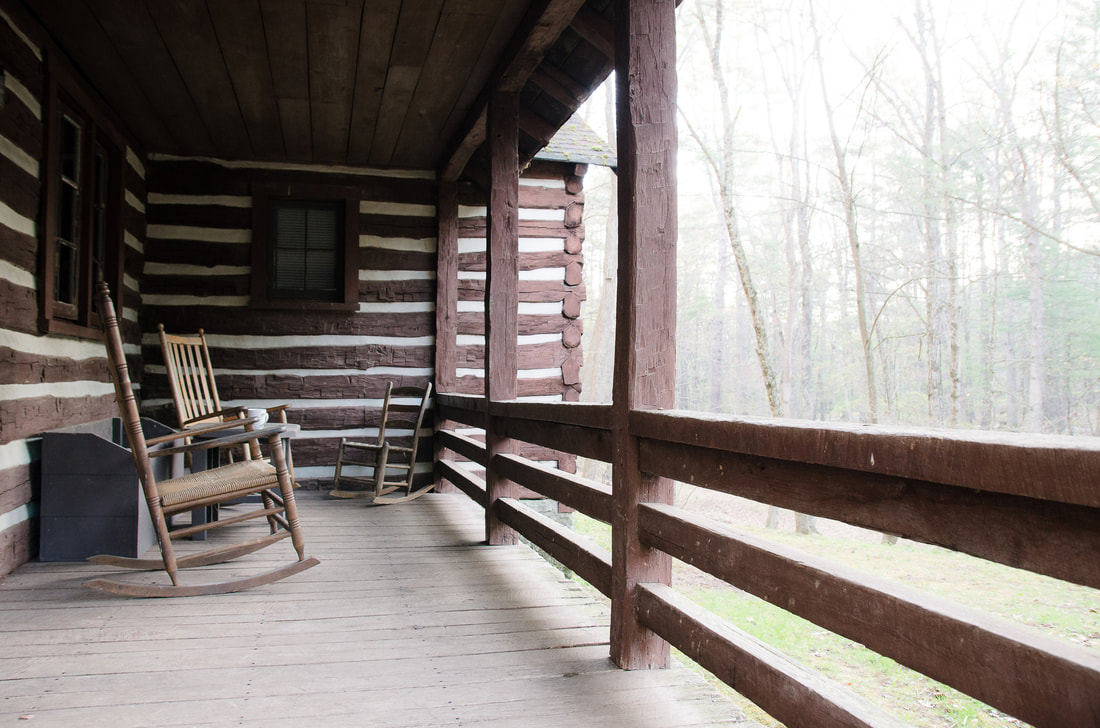 Rocking chair on porch of cabin in woods